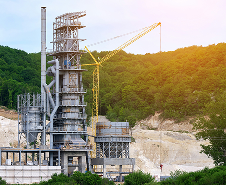 Industrial asphalt plant facility set against a forested hill